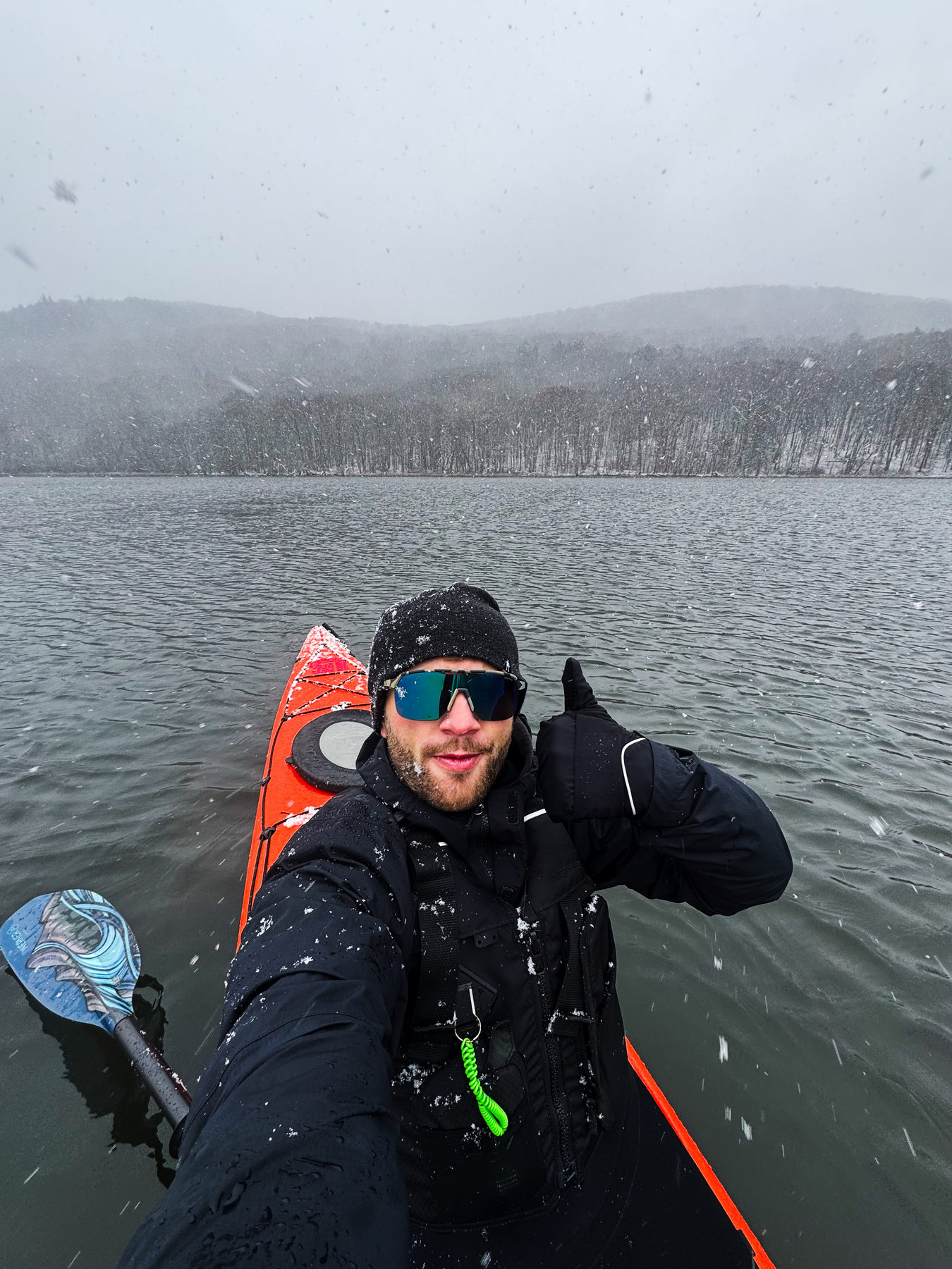 A kayaker paddling through falling snow